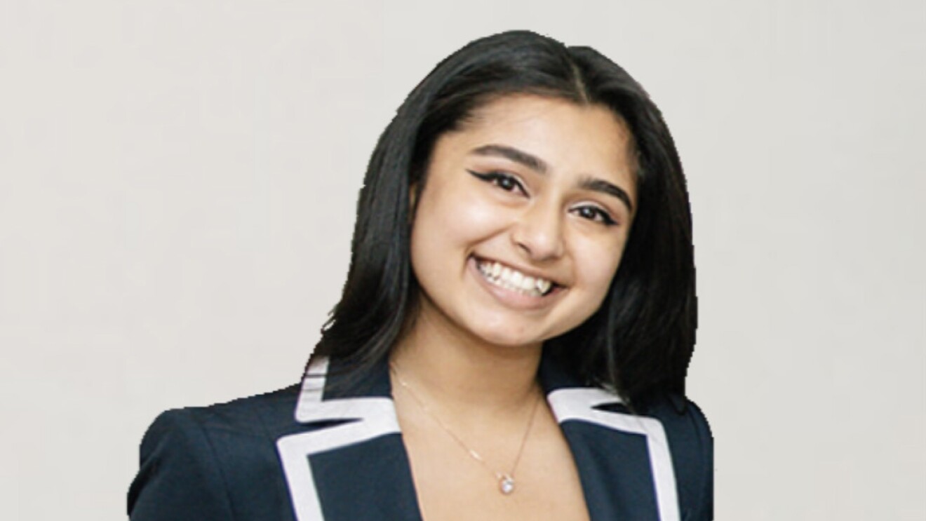 An image of a young woman smiling for a photo with a white background behind her.