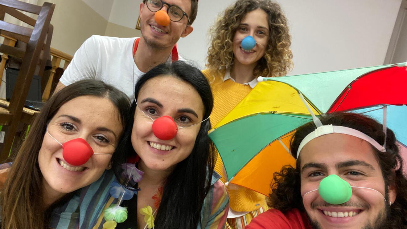Primo piano dei dipendenti Amazon durante il corso di clownterapia. Indossano nasi di gomma rossi e verdi e sono travestiti da clown. 
