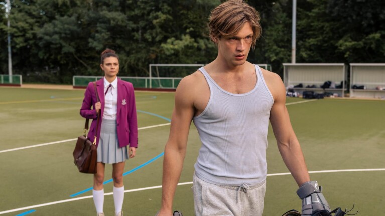 Damian Hardung and Harriet Herbig-Matten on a sports field during a scene of Maxton Hall