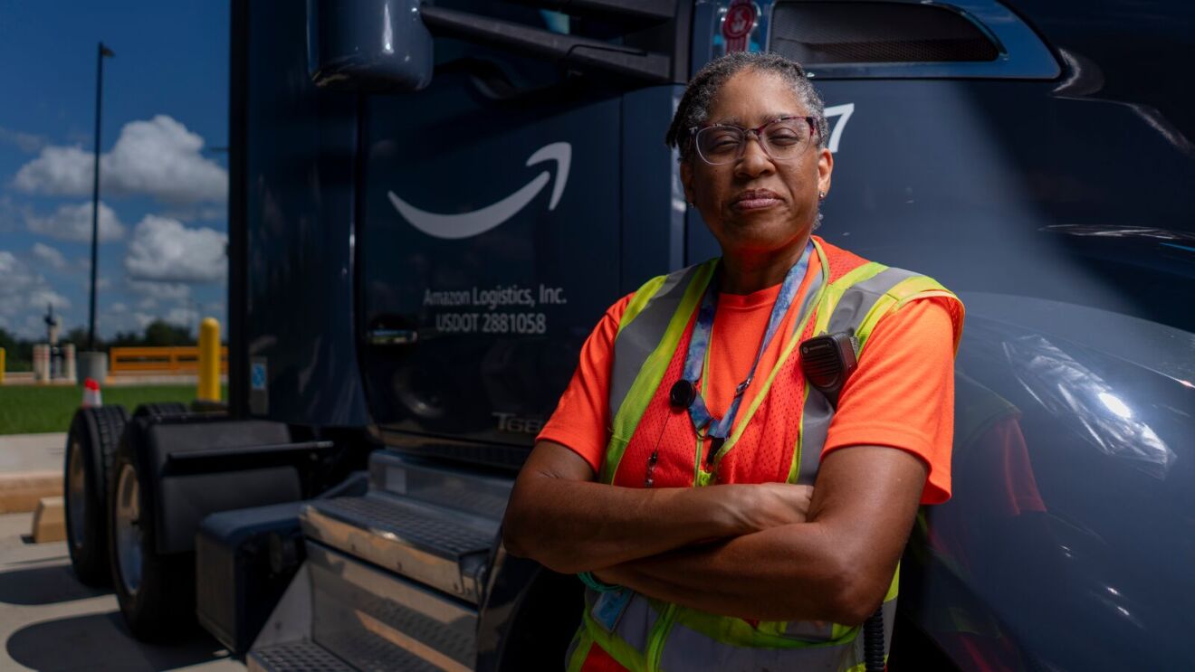 A woman standing next to an Amazon truck.