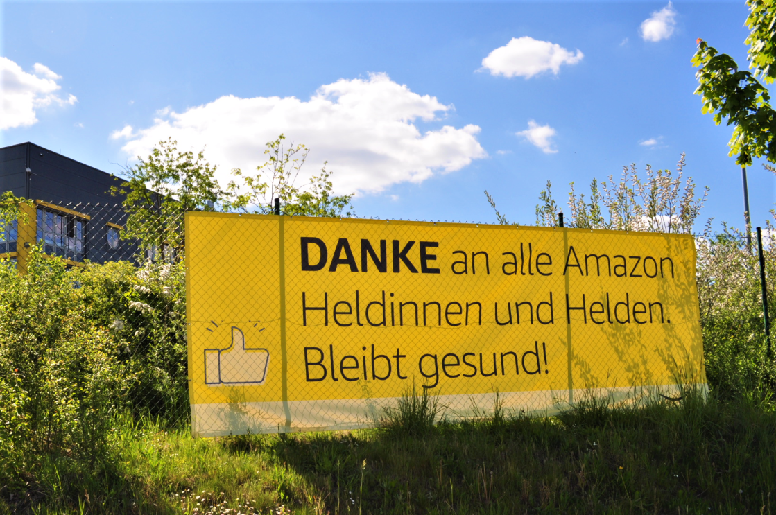 Gelbes Banner mit Aufschrift: Danke an alle Amazon Heldinnen und Helden. Bleibt gesund!