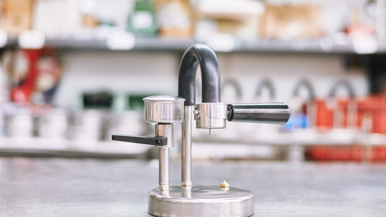 Foto di prototipo di caffettiera Kamira ormai molto simile alla versione finale. Si notano il manico e il collo dell'erogatore a U invertita ricoperti di plastica nera, in contrasto con le parti metalliche.