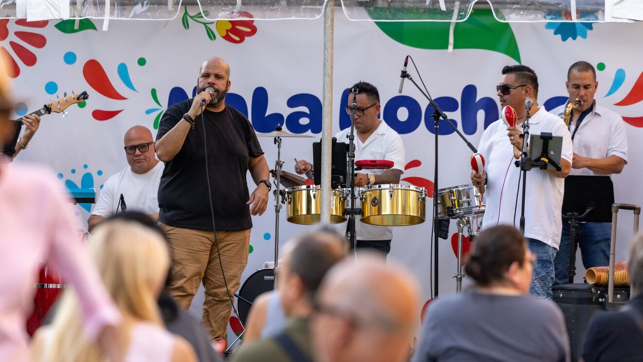 Musicians playing drums, guitar, and singing at 'NaLa Noches' event