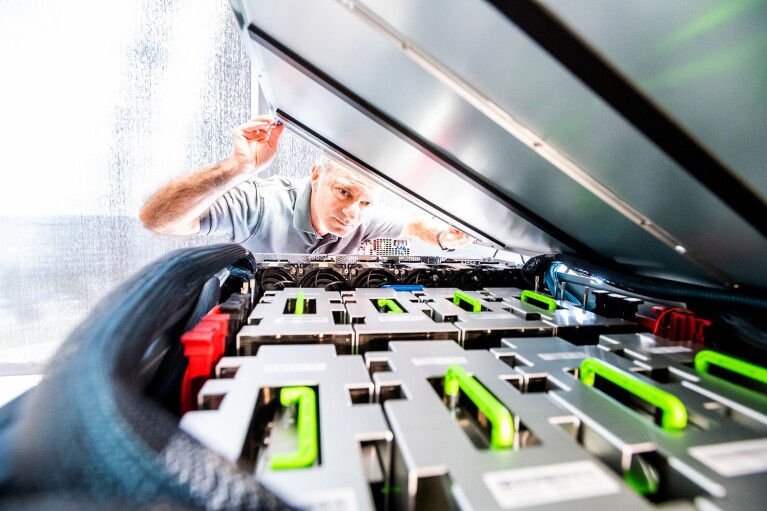 A man looks under a lid at a machine creating chips.