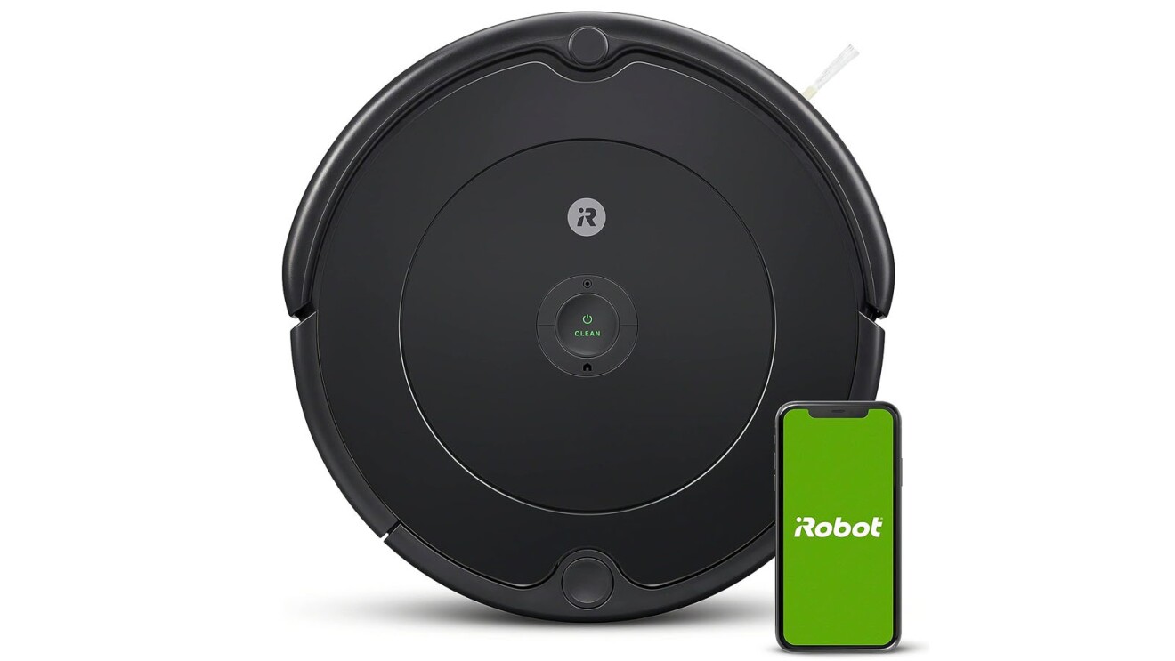 An image of a flat, round, small robotic vacuum cleaner with a smartphone in front of it that has a green and white logo on the screen that says "iRobot"