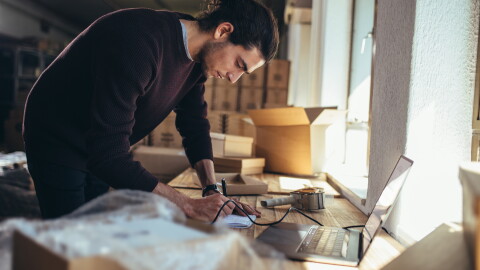 homme penché sur un bureau avec des boîtes en arrière-plan