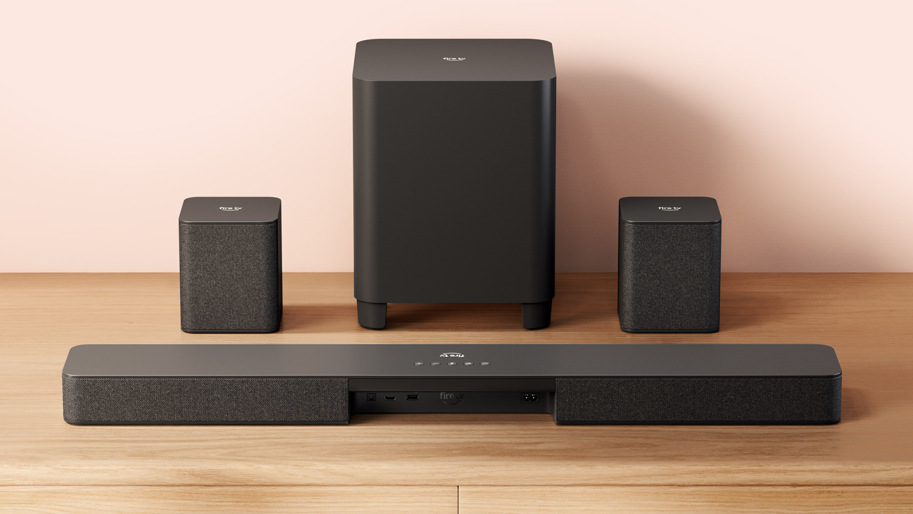 Fire TV Soundbar in the front with a subwoofer and surround sound speakers in the background.
