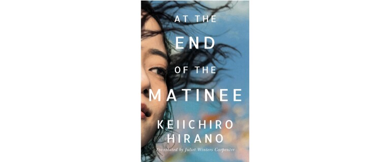 The book cover of "At The End Of The Matinee by Keiichiro Hirano" features a woman with dark hair blowing in her face looking out into the distance. The blue sky consumes the rest of the cover.