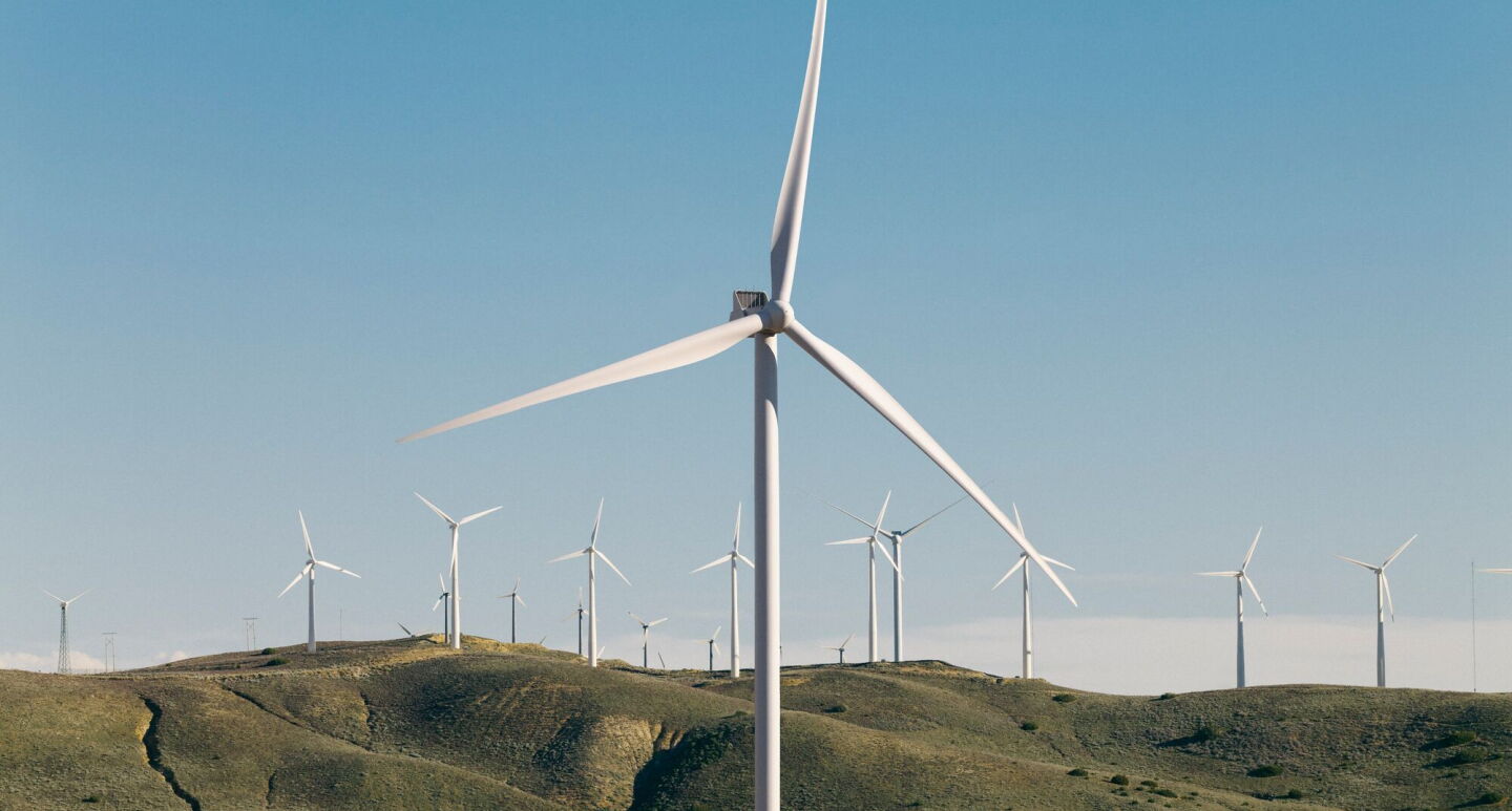 Wind farm on rolling hills with rows of turbines