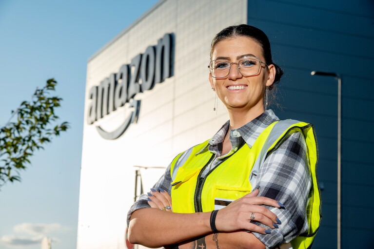 Amazon employee Diana Frunza in a safety vest while smiling outside a fulfilment centre