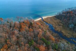 Autumnal landscape with azure water, riverine path, and fall woodlands