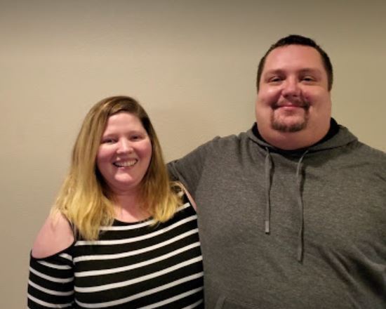 A woman and man stand together, smiles on their faces.