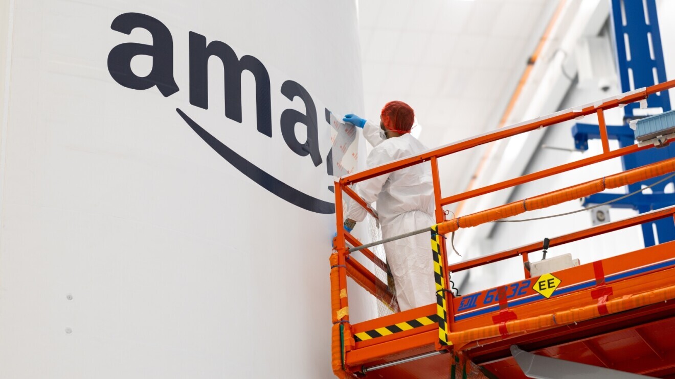 Amazon branding being applied to rocket by person in protective gear