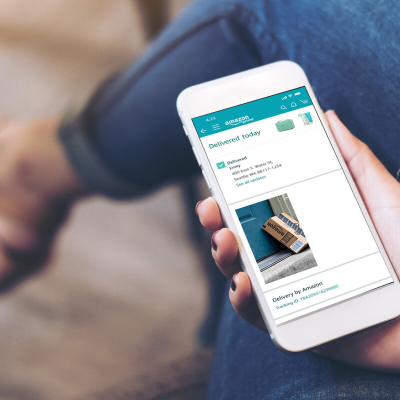 A woman looking at a phone and on the screen you can see the delivery confirmation of an Amazon package.