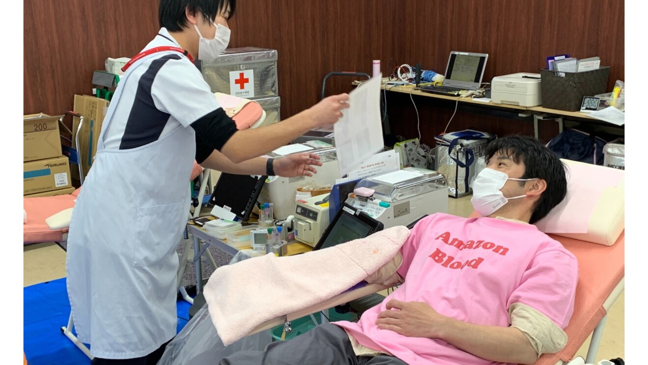 ベッドに横になって採血中の関さんと看護師さんの写真