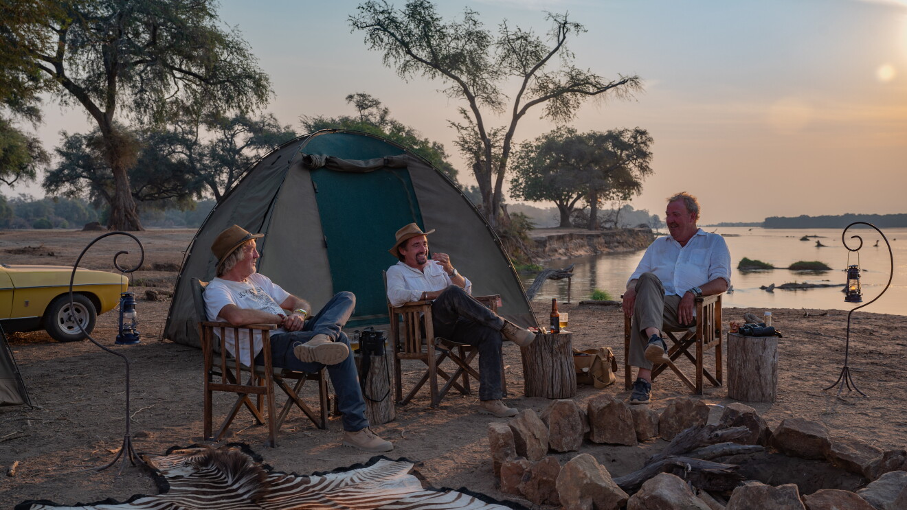 Three men sit around a campfire 