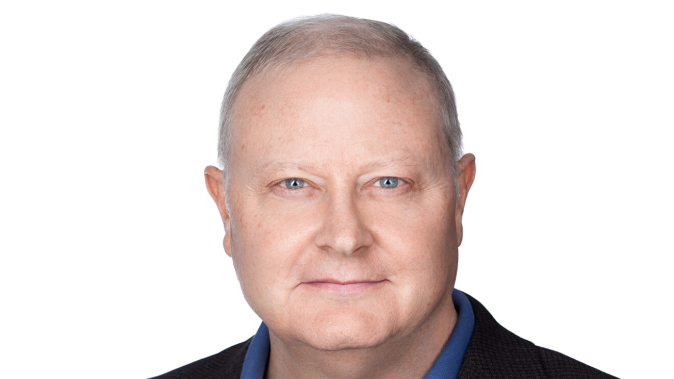 A headshot image of a man with a white background behind him.