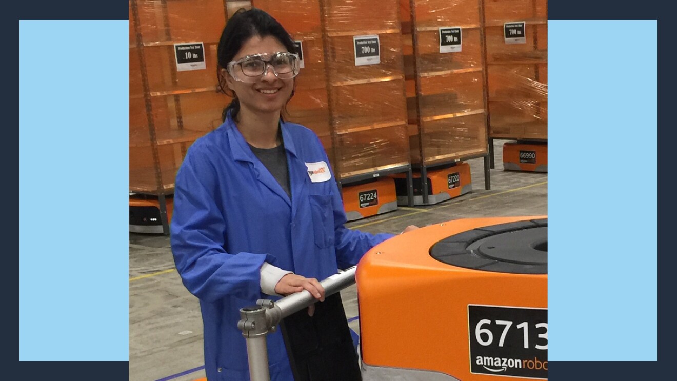 Amazon robotics employee wears safety goggles and pushes a robot on a sturdy cart.