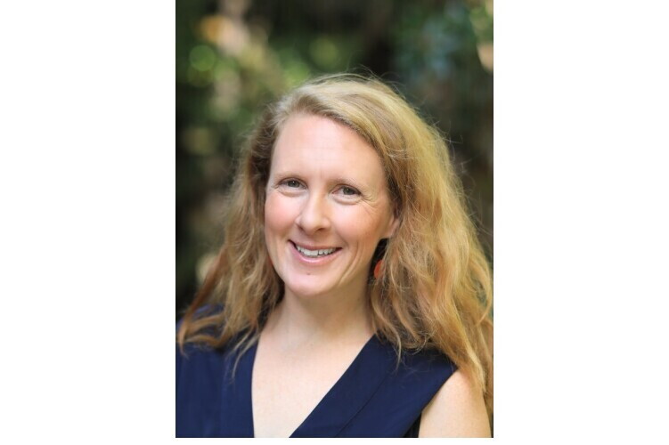 Dr. Annie Burgess, Lab Director, Earth Science Information Partners (ESIP). Sie hat dickes, blondes Haar mit einem Seitenscheitel, trägt ein dunkelblaues Oberteil und lächelt in die Kamera.