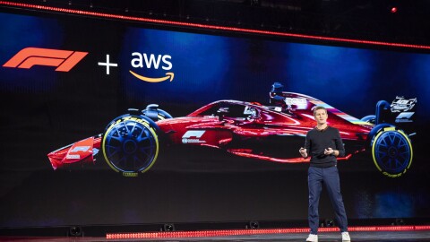 Rob Smedley, Formula 1 engineer standing on stage at the AWS re:Invent 2019 event. He is in front of a large screen with a Formula 1 car on it. 