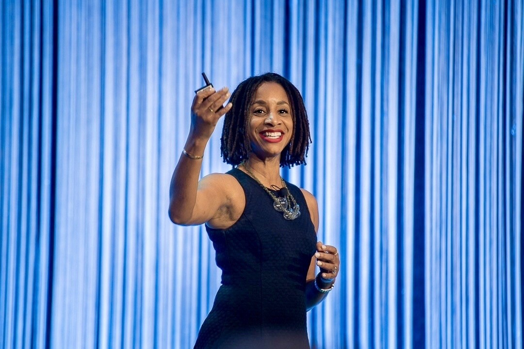 A woman smiles as she gives a presentation.