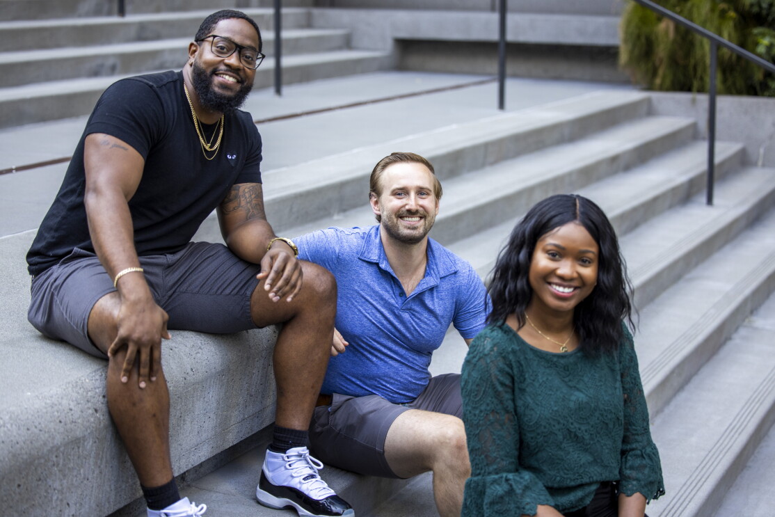Two women and a man sit on a concrete staircase.
