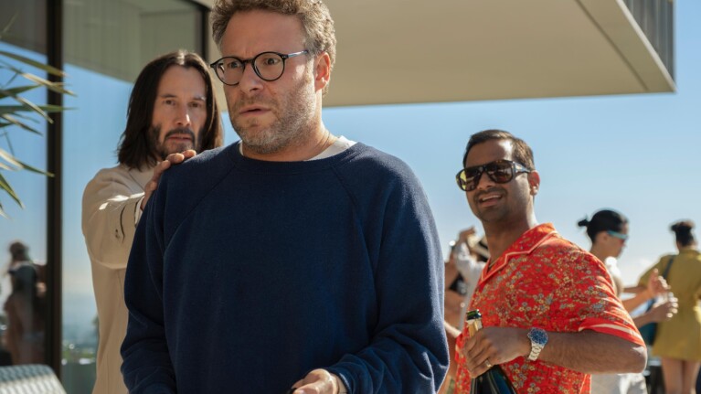 Three men at outdoor gathering, one looking surprised