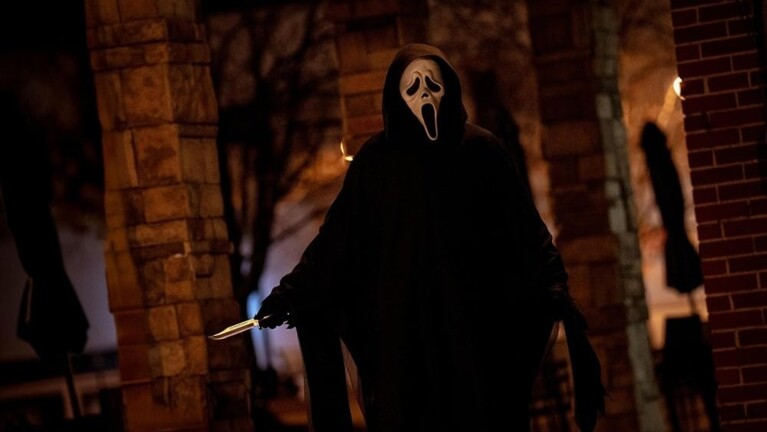 Horror character wearing a dark cape and a white mask, holding a knife 