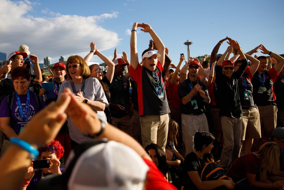 2018 Special Olympics USA Games athletes cheer at the closing ceremony. Many of the atheletes are seen holding their arms up, above the head, with fingers touching. Other individuals are clapping.