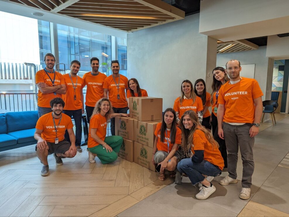 Amazon Mitarbeiter:innen In orangenen T-Shirts in Italien stellen Produkte für Spenden zusammen.