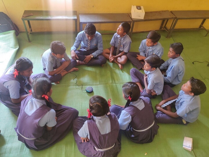 A bunch of school children surrounding an Echo device. 