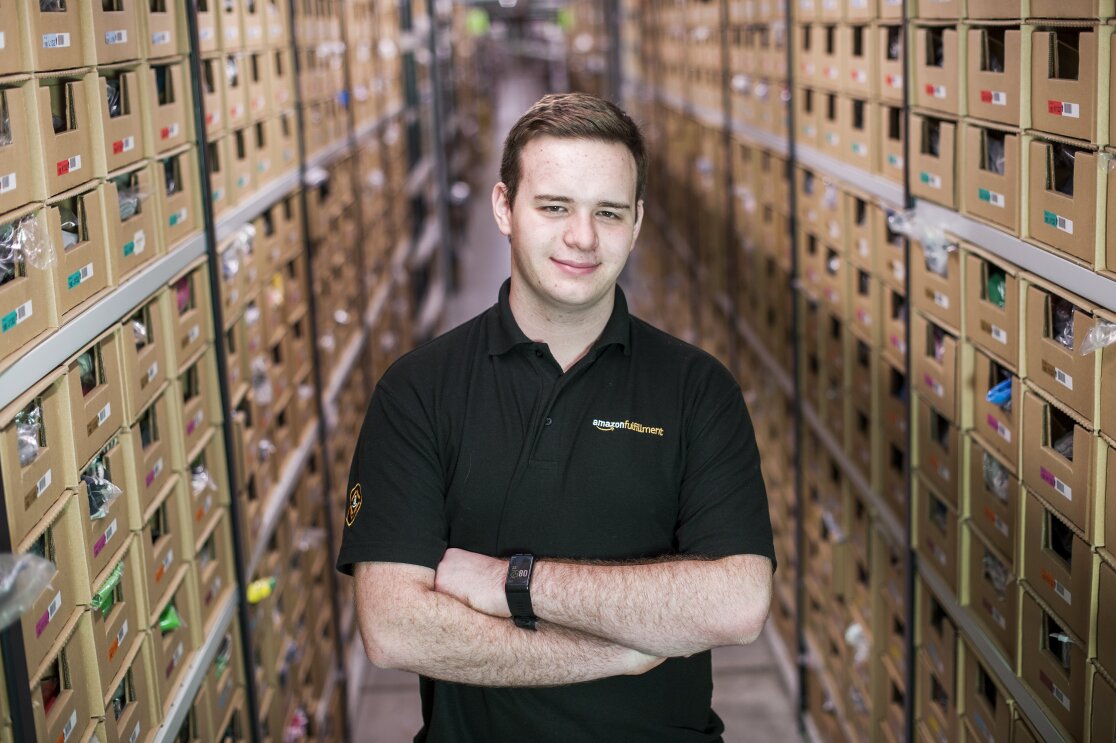 Jonathon Williams stood in Amazon Fulfilment Centre with arms crossed
