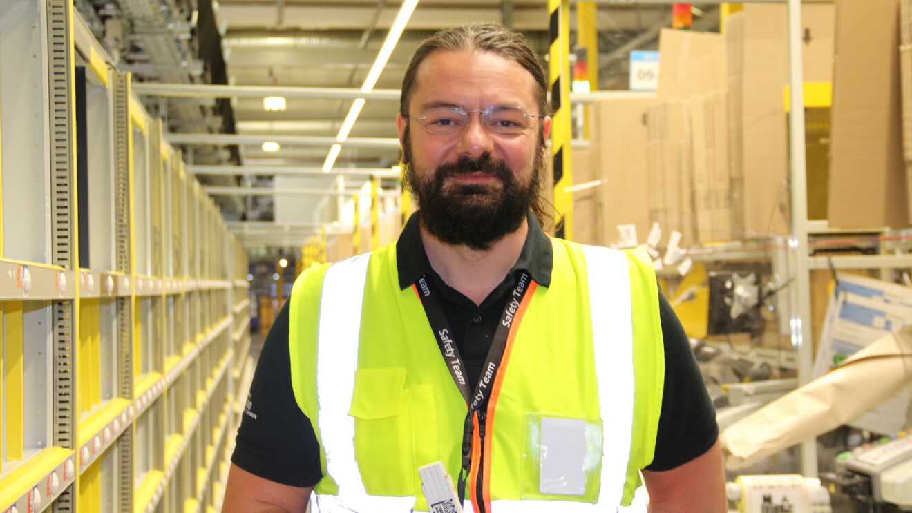 Amazon-Arbeitssicherheitsexperte Lucian Geiger mit gelber Weste im Logistikzentrum.