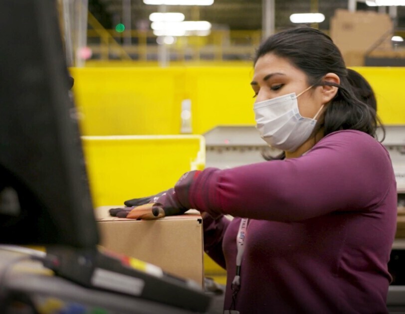 Amazon employee performing work duties while wearing a mask during the COVID-19 pandemic.