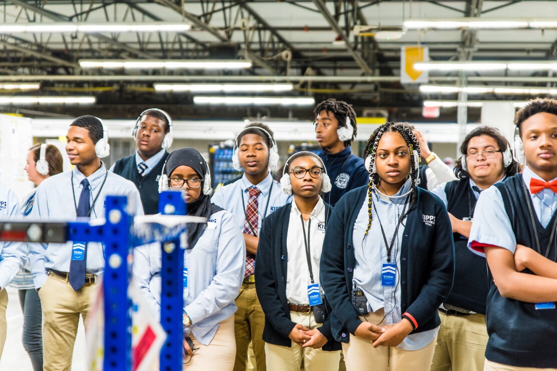 High school students wearing school uniforms and headphones participate in an Amazon fulfillment center tour in Etna, Ohio.