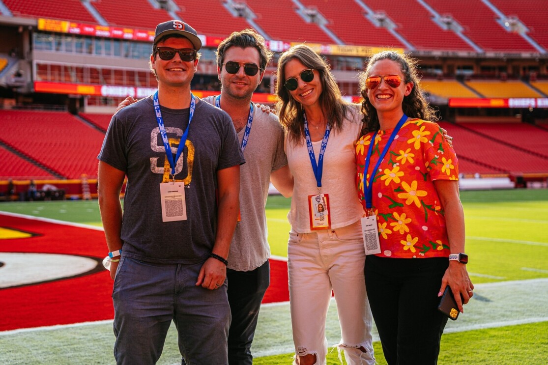 Gigi Clark smiles for a photo with her team on a football field before a Thursday Night Football game