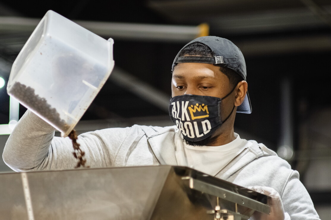 A man pours coffee beans into the top of a machine.