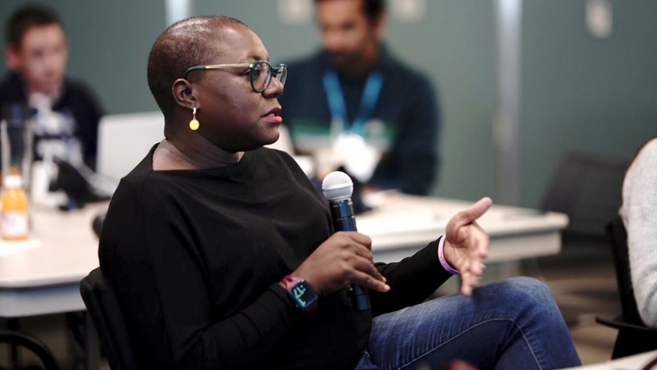 CaSondra Devine holding a microphone while she talks.