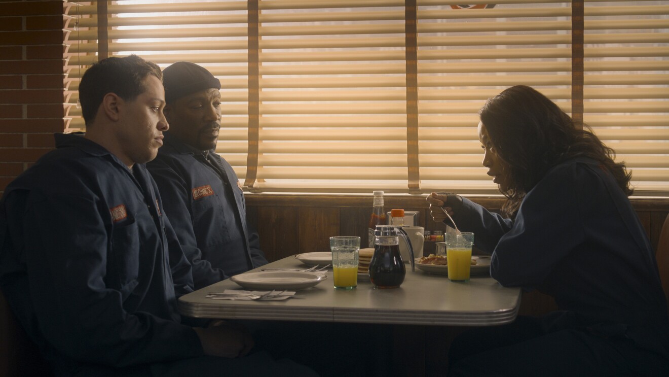 Diner scene with three uniformed people at booth eating breakfast