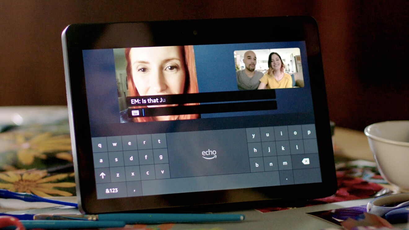 一个回声显示显示的多画面视频电话之间的一个女人,和一对夫妇。下面的视频是一个屏幕键盘。