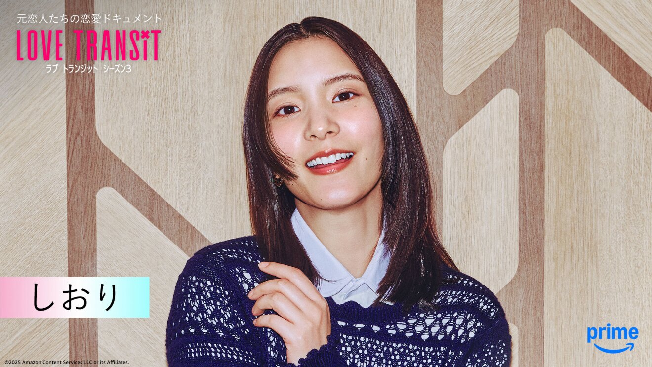 木目調の壁の前に立つ人物のバストアップ。左上隅に「LOVE TRANSIT」の文字。左下に「しおり」と名前が表示されている。
