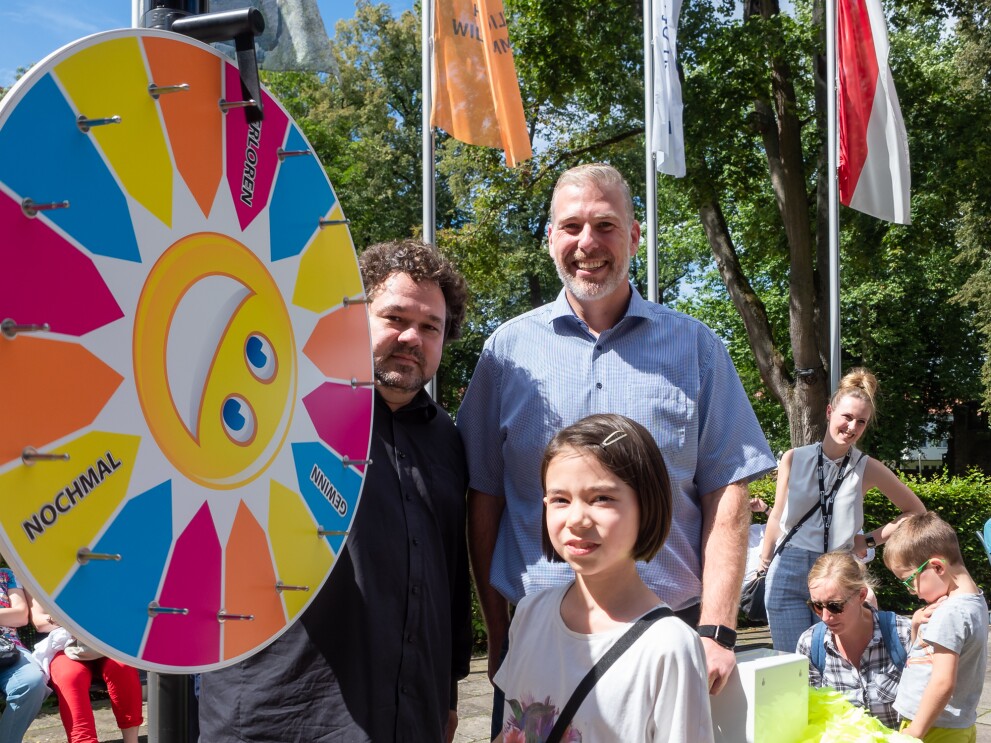 Ein Glücksrad: Davor steht ein Mädchen mit braunen Haaren.