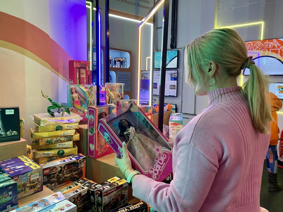 A young woman holding a barbie at the Amazon second chance store