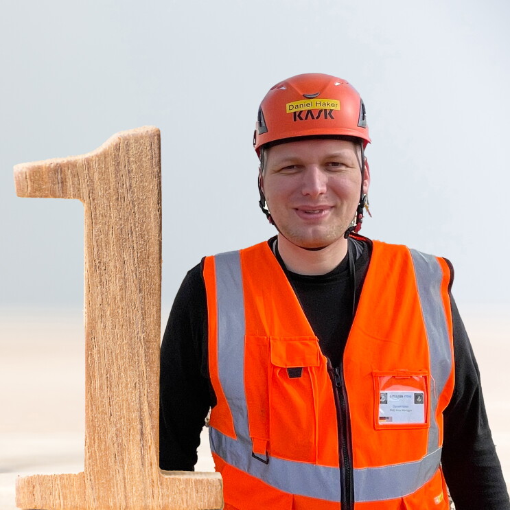 Daniel mit Helm und Sicherheitsweste vor dem neuen Logistikzentrum in Gera.