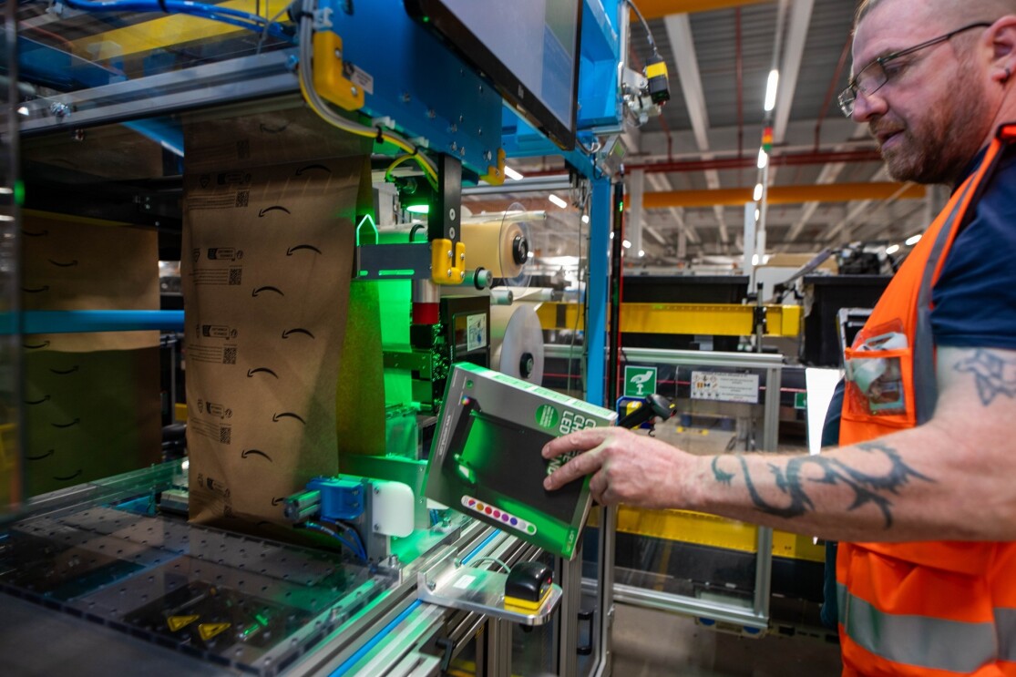 Umweltfreundliche Verpackung bei Amazon: Foto der Maschine und einem Mitarbeiter, der mit der Maschine arbeitet.