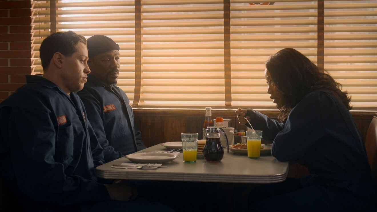 Two men and a woman talk at a diner