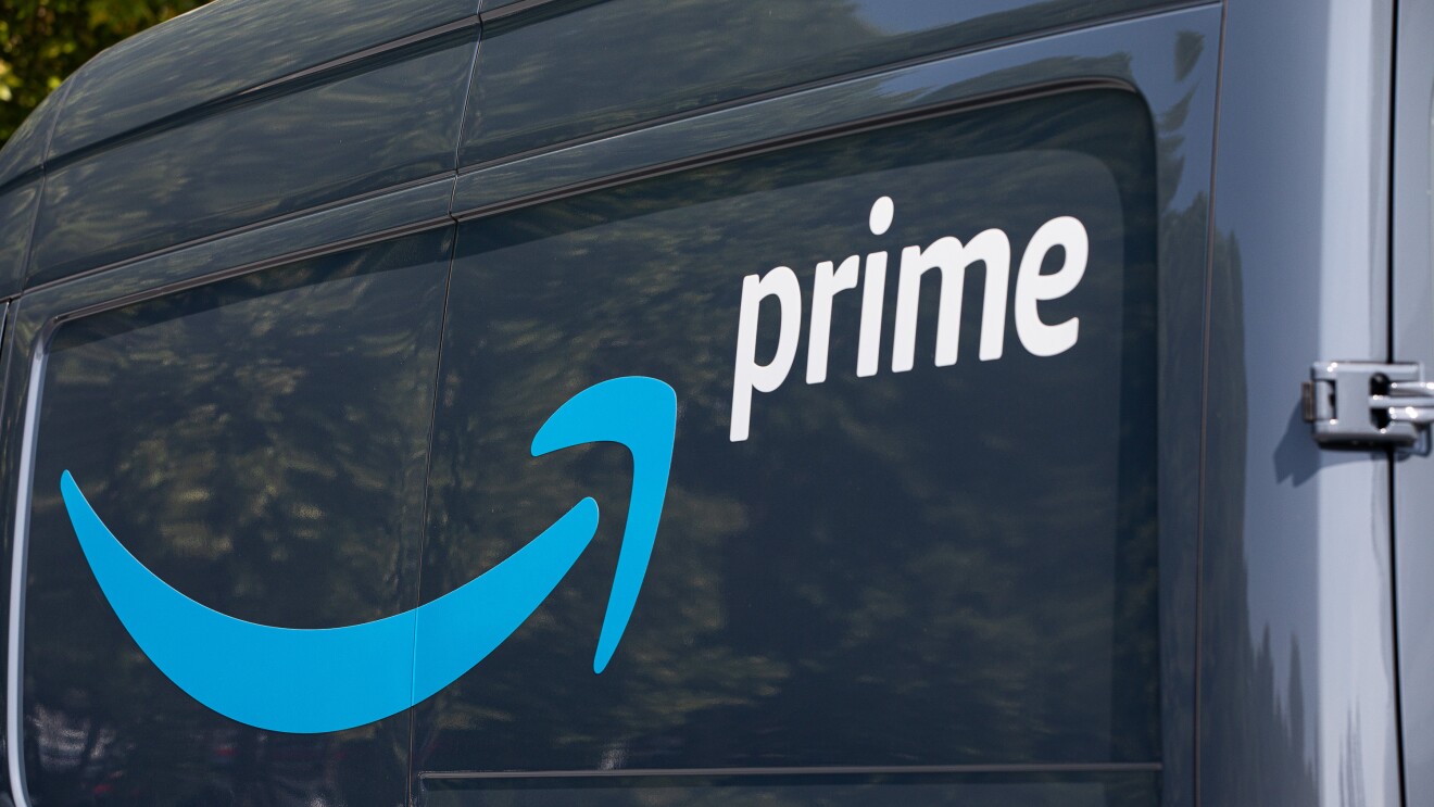 Parte trasera de una furgoneta de reparto. Letras Prime en blanco y la sonrisa de Amazon en azul.