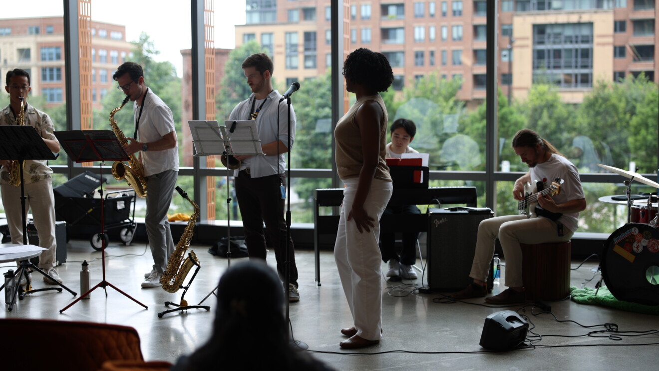 Jazz ensemble practicing near large windows overlooking apartments