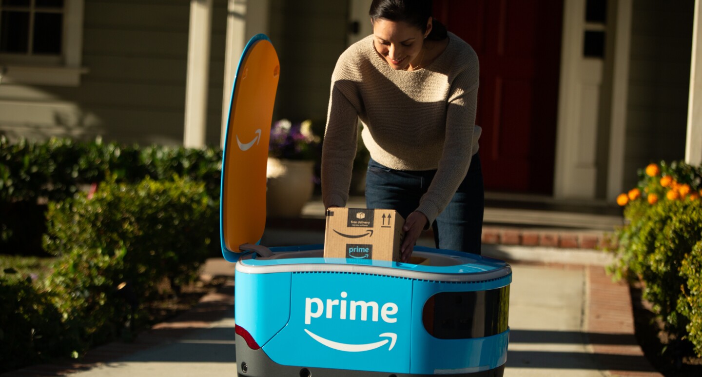 A woman retrieves her package from Scout in front of a home.