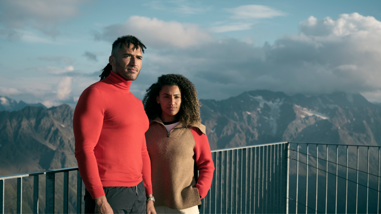 Stylish couple stood atop mountains, looking dramatically into distance